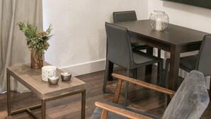 Een eetruimte met een houten tafel, zwarte stoelen en een bloevas op een bijzettafeltje.