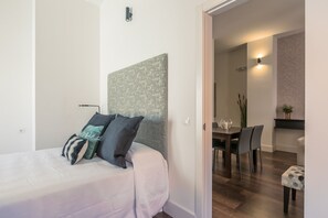 A bedroom with a bed, a headboard, and a dining area with chairs and a table. - Sierpes Luxury Premium de 2 -1 bedroom (Sevilla)