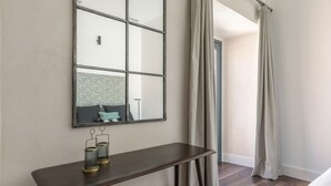 A room with a large mirror, a small table with two candle holders, and a view of a hallway with a door. - Sierpes Luxury Premium de 2 -1 bedroom (Sevilla)