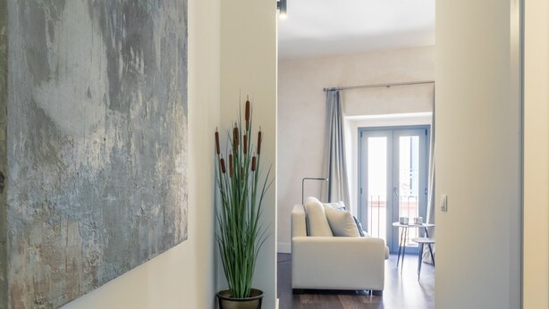 A modern living room with a white sofa, a potted plant, and a large abstract painting on the wall. - Sierpes Luxury Premium de 2 -1 bedroom (Sevilla)