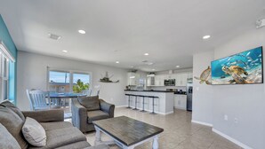 A spacious living area with a gray sofa set, a wooden coffee table, and a kitchen in the background. - Dock, Pool, FREE RAMP, Kayaks, Jacuzzi, Amazing Ocean Views Pets are Welcomed! (Marathon)