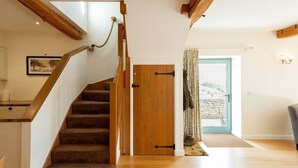 A staircase with wooden steps and a handrail, a wooden door, and a view of the outdoors through a door. - Two Bedroom Family Friendly Holiday Cottage in the Cotswolds - Will's Cottage (Stroud)