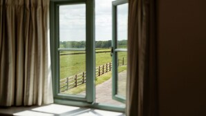 A window with a view of a green field and a wooden fence. - Two Bedroom Family Friendly Holiday Cottage in the Cotswolds - Will's Cottage (Stroud)