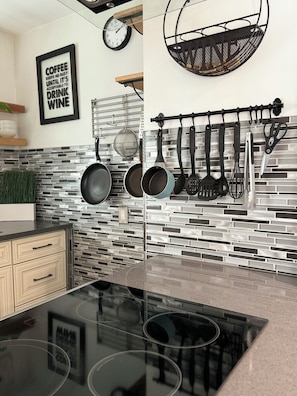 A modern kitchen with a black countertop, hanging pots, a clock, and a framed quote on the wall. - KING size bed- walk to the BEACH- Air Conditioner- Bunk beds- Pullout Couch (Long Beach)