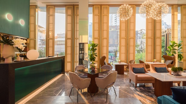 A modern hotel lobby with a reception desk, seating area, and large windows offering city views. - SQ Boutique Hotel (Bangkok)