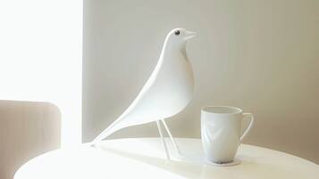 A white bird figurine and a white mug on a round table.