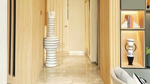 A modern hallway with a marble floor, a unique white and black striped sculpture, and a seating area with a grey sofa and a small table. - SQ Boutique Hotel (Bangkok)