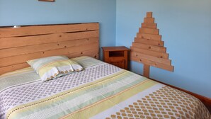 Una cama con cabecera de madera, una colcha estampada y una mesita de noche de madera.