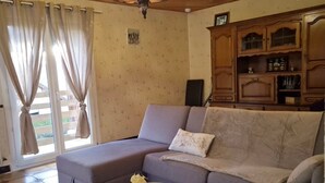Una sala de estar con un sofá modular, una mesita redonda y un mueble con puertas de vidrio.