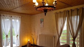 Una habitación acogedora con techo de madera, un sofá, una mesa y un radiador.