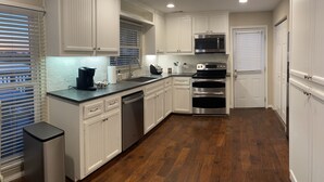 A modern kitchen with white cabinetry, stainless steel appliances, and a wooden floor. - Waterfront Terramar Getaway, Amazing Sunsets, Outdoor Bar, Kayak, Beach, Fishing (Galveston)