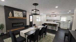 Une cuisine moderne avec des meubles blancs, un îlot central et un coin repas comprenant une table et des chaises noires.