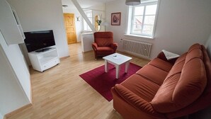A modern living room with a sofa, a coffee table, and a television. - Whg. Langeness - Haus am Deich (Utersum)