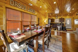 Un intérieur en bois avec une table à manger pour six personnes, un plancher en bois et un coin cuisine.