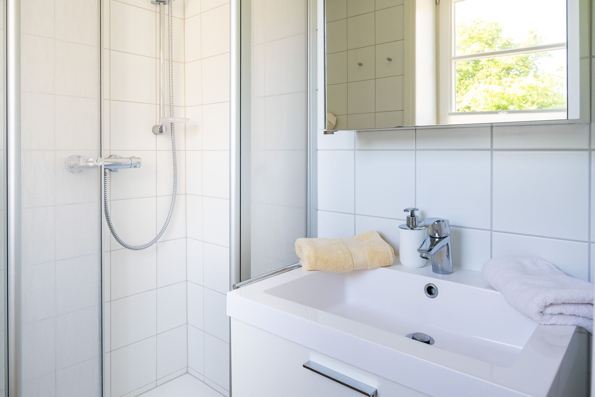 A bathroom with a shower, a sink, and a mirror.