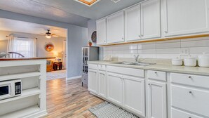A kitchen with white cabinets, a wooden countertop, and a built-in microwave.