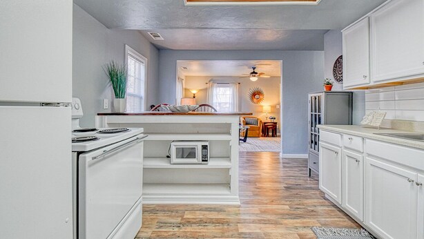 A kitchen with white cabinets, a microwave, and a stove. There is a skylight above the kitchen.