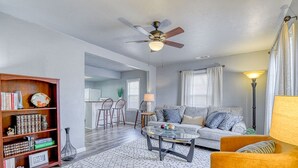A living room with a sofa, coffee table, bookshelf, and a ceiling fan.