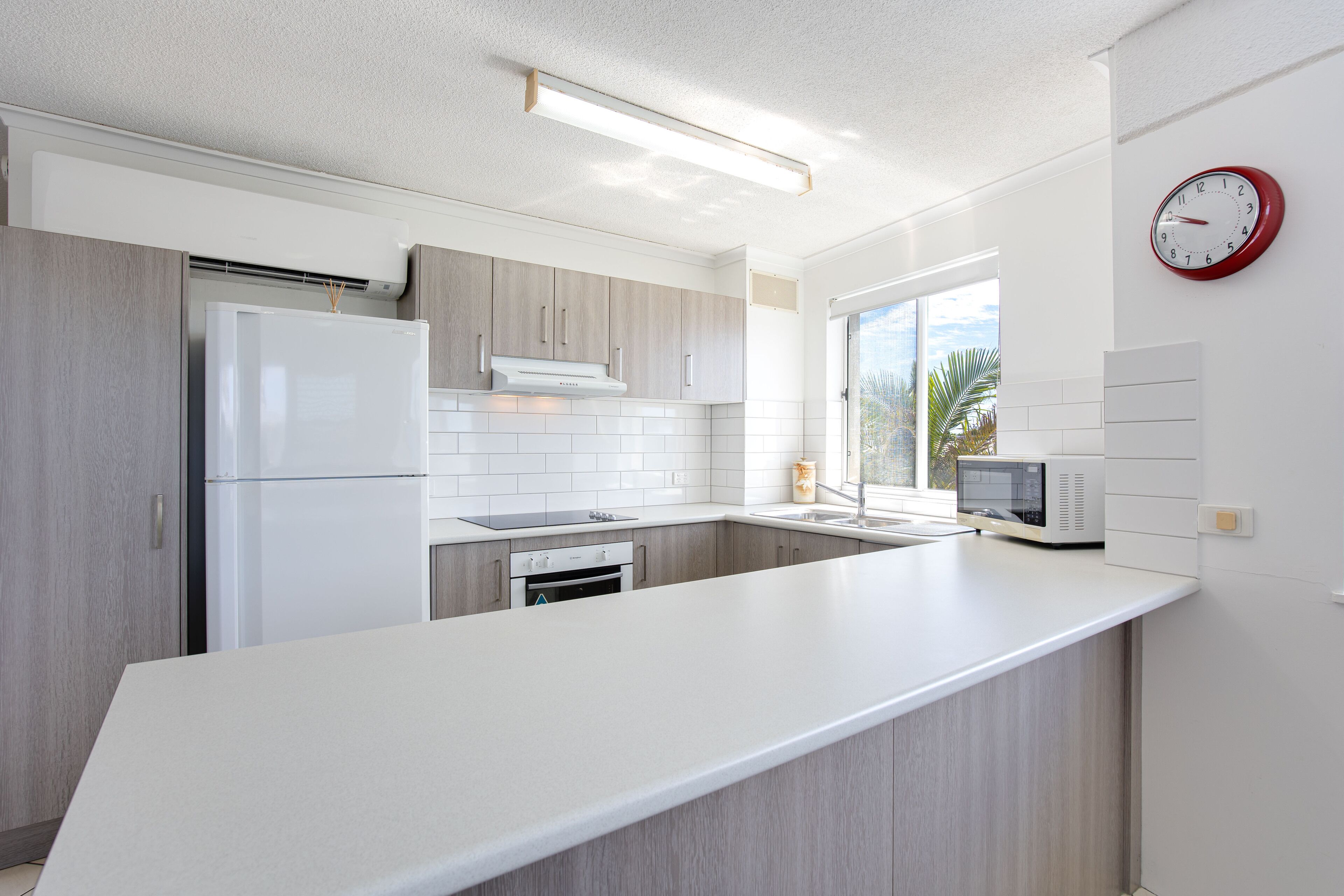 A modern kitchen with a large island, white cabinetry, and a microwave.