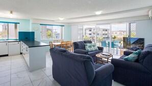 A modern apartment with a kitchen, dining area, and living room. - Coral Sea Apartments (Maroochydore)
