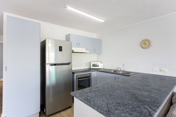 Una cocina moderna con un refrigerador de acero inoxidable, un microondas y un horno empotrado.