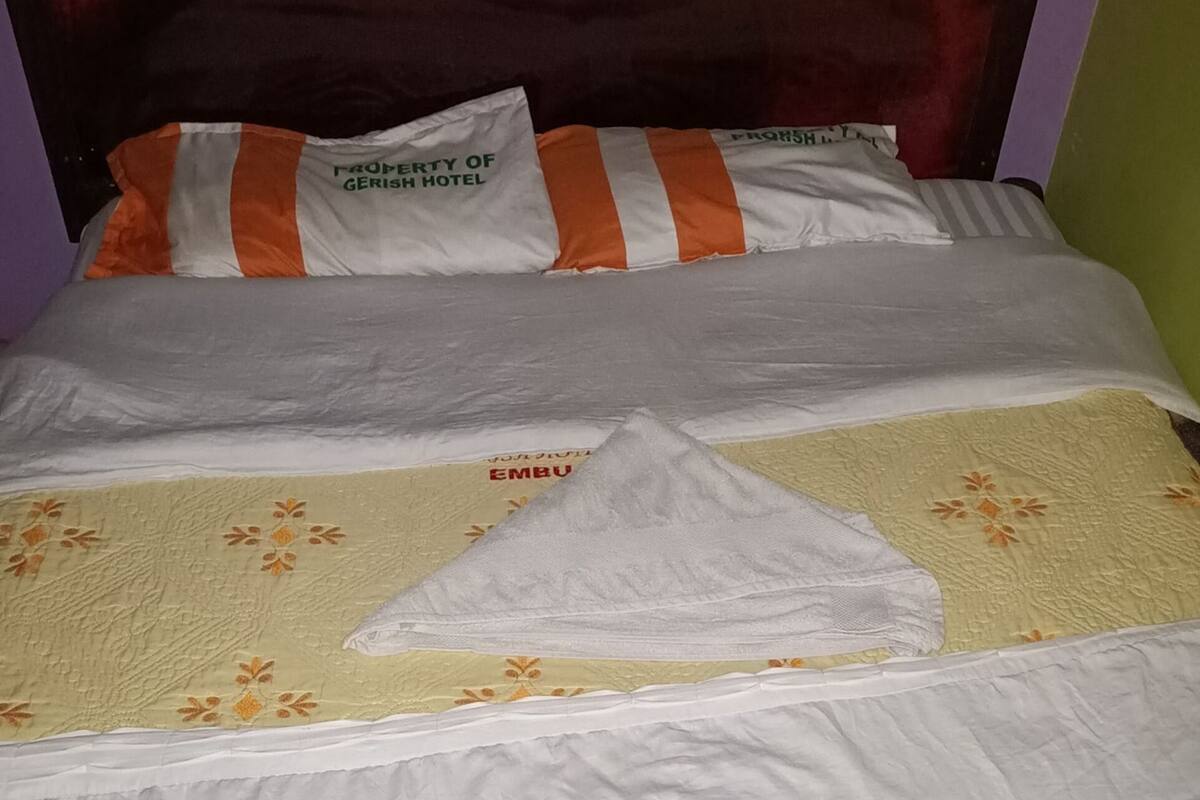 Ein Bett mit weißer Bettwäsche, gestreifte Kissen und einer Decke mit Blumenmuster.