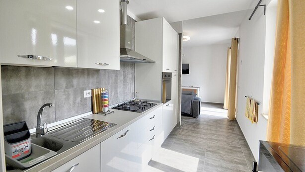 A modern kitchen with white cabinets, a stainless steel sink, and a built-in stove.