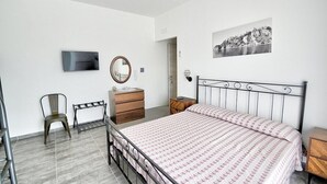 A bedroom with a bed, a dresser, a chair, a television, and a framed picture on the wall.