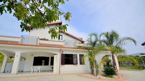 A two-story house with a covered patio, white walls, and a red roof. - Villa Olga E: A cozy and welcoming apartment that is part of a villa situated in a quiet location, a few minutes from the town center, with Free WI-FI. (Agropoli)