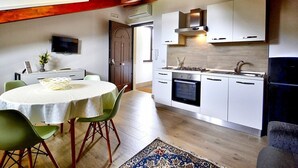 A modern kitchen with white cabinets, a stove, and a sink. There is a dining area with a table and chairs. - Villa Olga E: A cozy and welcoming apartment that is part of a villa situated in a quiet location, a few minutes from the town center, with Free WI-FI. (Agropoli)