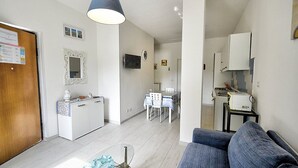Un espace de vie compact comprenant un coin cuisine, un coin repas et un coin salon avec un canapé.