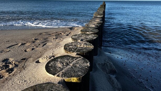 Una playa con un muelle de madera que se adentra en el mar.