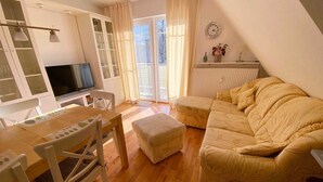 Una sala de estar acogedora con un sofá, una televisión y un comedor con mesa y sillas.