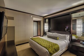Habitación de hotel moderna con una cama grande, una mesita de noche, un espejo y vistas al pasillo.