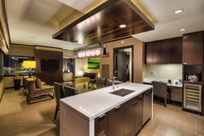 Una cocina moderna con una isla central, electrodomésticos integrados y un comedor con vistas a la ciudad.