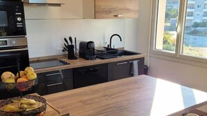 Una cocina moderna con encimera de madera, taburetes negros y amarillos, y vistas al exterior a través de grandes ventanales.