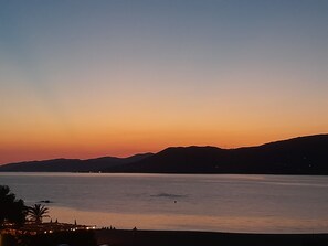 A coastal sunset view with a calm sea, distant mountains, and a few people on the shore. - Propriano: Sea view, Waterfront (Propriano)