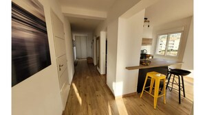 Una cocina moderna con encimera de madera, un taburete amarillo y vistas al exterior a través de una ventana.
