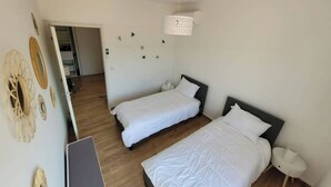 Una habitación con dos camas, un escritorio y una lámpara colgante.