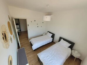 A room with two beds, a desk, and a hanging light fixture. - Propriano: Sea view, Waterfront (Propriano)