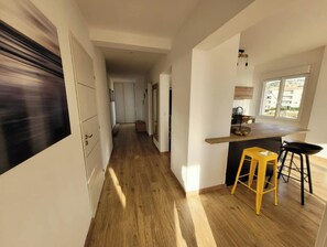 Una cocina moderna con encimera de madera, un taburete amarillo y vistas al exterior a través de una ventana.
