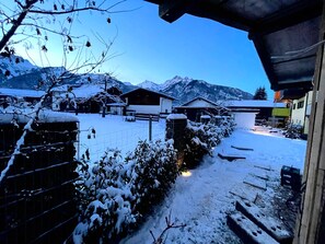 A snow-covered village with houses, a path, and mountains in the background.