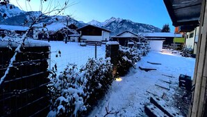 Un pueblo cubierto de nieve con casas, un sendero y montañas al fondo.