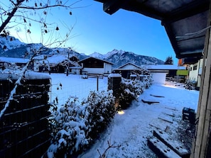 A snow-covered village with houses, a path, and mountains in the background.