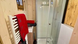 Un baño pequeño con ducha, inodoro y lavamanos.