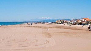 A wide sandy beach with buildings in the background and mountains in the distance. - Peaceful Escape in Argeliers (Argeliers)