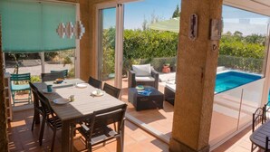 A covered patio with a dining table and chairs, a pool, and a view of greenery. - Peaceful Escape in Argeliers (Argeliers)