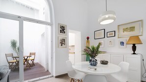 A modern dining area with a round table, white chairs, and a vase with flowers.