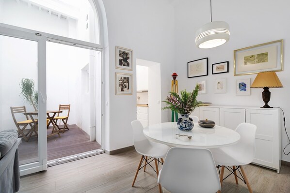 A modern dining area with a round table, white chairs, and a vase with flowers.