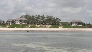 Una propiedad frente a la playa con varias casas, una playa arenosa y una vista despejada del océano.